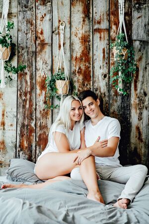 Portrait of happy couple sitting on bed at homeの写真素材