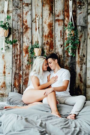 Portrait of romantic couple sitting on bed in bedroomの写真素材