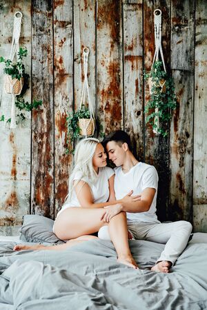 Portrait of happy couple sitting on bed at homeの写真素材