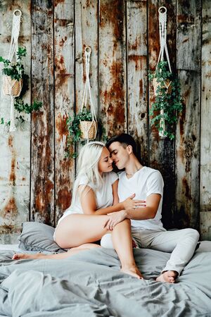 Portrait of romantic couple sitting on bed in bedroomの写真素材