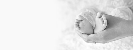 happy family concept. Beautiful conceptual image of Maternity. Baby feet in mother hands closeup. Mom and her Child. Black and white banner. copy spaceの写真素材