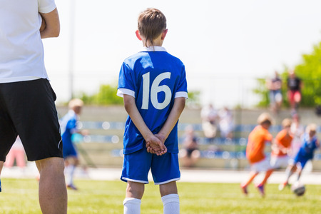 Young boy and soccer coach watching football match. Youth reserve player ready to play