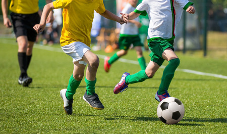 young boys playing football soccer game. Running players in yellow and white uniformsの写真素材