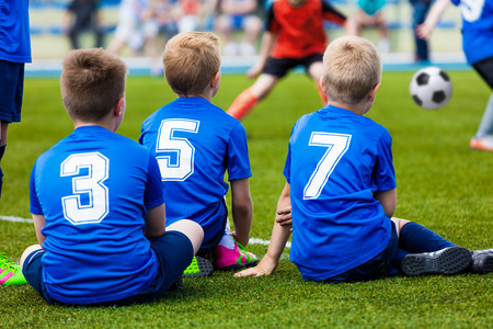 Young soccer team. Reserve players sitting together and watching football soccer tournament match for youth teams.の写真素材
