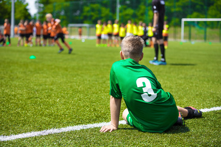 Young caucasian soccer player sitting on grass. Youth football backgroundの写真素材