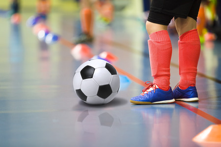 Children training soccer futsal indoor gym. Young boy with soccer ball training indoor football. Little player in light red sports socksの写真素材