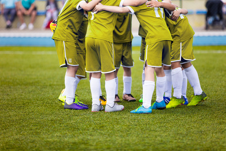 Young football soccer players in yellow sportswear. Young sports team on pitch. Pep talk before the final match. Soccer school tournament. Children on sports field.の写真素材