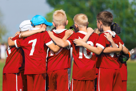 Children Soccer Team. Children Football Academy. Kids Soccer Players in Red Shirts Standing Together on the Pitch. Youth Soccer Motivational Speech. Coach Motivational Talk With Young Boysの写真素材