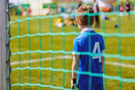 Young boy as a soccer goalkeeper during football match ready to saveの写真素材