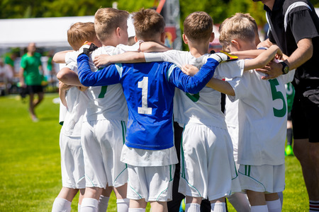 Young football soccer players in sportswear. Coach Motivating Kids In Sport. Youth sports team with football coach. Pep talk with coach before the final match. Soccer school tournamentの写真素材