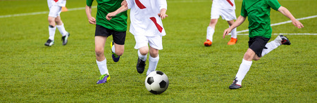 Football match for young players. Training and football soccer tournament for children. Youth soccer competition betweeen two footballers. Red team versus blue team の写真素材