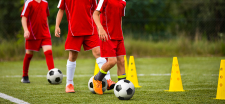 Soccer camp for kids. Children training soccer skills with balls and cones. Soccer slalom drills to improve football dribbling fastの写真素材