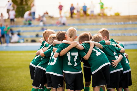 Young football soccer players in sportswear. Young sports team with football coach. Pep talk with coach before the final match. Soccer school tournamentの写真素材