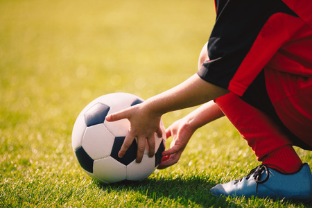 Young boy holding football ball. Soccer game for children. Youth outdoor sport backgroundの写真素材