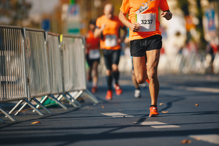 Marathon running race, people feet on autumn road. Runners run urban marathon in the the cityの写真素材