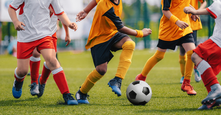 Children Play Soccer Game. Young Boys Running and Kicking Football Ball on Grass Sports Fieldの写真素材