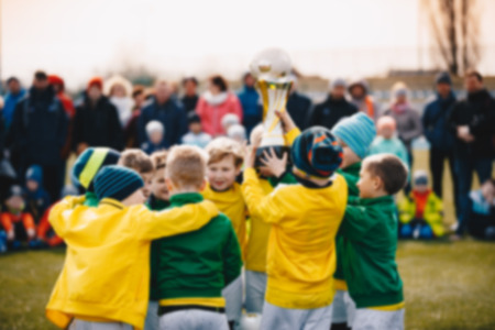 Blurred Background of Kids Sport Team with Trophy. Kids Celebrating Football Championship. Happy Young Soccer Players Holding Golden Cup. Football Team Winning Youth Soccer Tournamentの写真素材