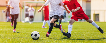 Junior Soccer Match Duel. Football Game For Youth Players. Boys Playing Soccer Match on Football Pitch. Football Stadium and Grassy Field in the Backgroundの写真素材