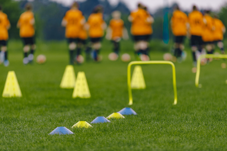 Sports Soccer Football Training Practice Session. Blurred Sports Background. Soccer Training Equipment and Football Players on Summer Grass Fieldの写真素材