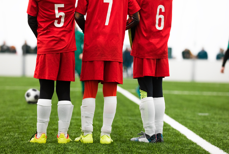 Junior Soccer Players Standing in a Wall. Free Kick Situation During Football Match. Players Wearing Red Soccer Jersey Shirts with Numbers on Back. Soccer Tournament Gameの写真素材