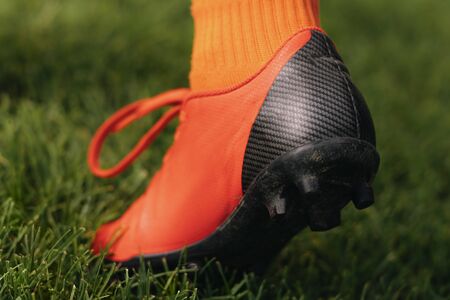 Close-up stud shoe on green lawn background. Soccer football cleat on grass pitch. Soccer player making step in soccer shoes. Detailed soccer backgroundの写真素材