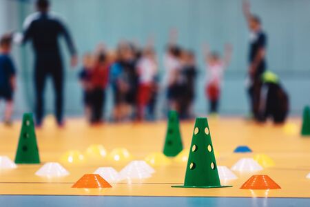 Indoor soccer training during the winter. Futsal practice for children. Kids with futsal coach. Physical education unit of soccer. Futsal training field with colourful equipment, cones and markersの写真素材