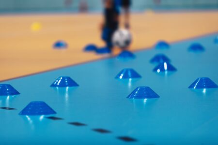 Indoor soccer training during the winter. Futsal training field with blue cones. Indoor football...