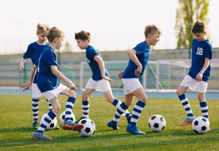 Kids Sports: Teaching Children to Improve Soccer Skills. Football camp for kids. Boys practice dribbling in field. Players develop skills. Children training with balls. Soccer slalom drillsの写真素材