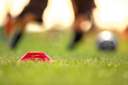 Sport red training marker on a grass training venue. Players running in a blurred background....