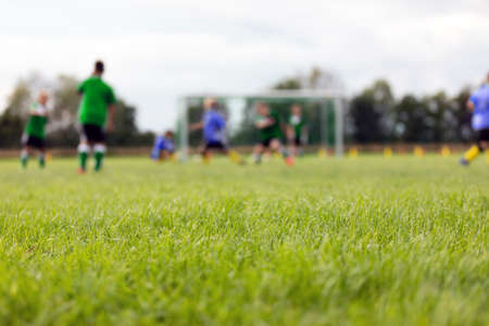 Blurred background of football field. Boys playing soccer game. Kids in two teams playing tournament matchの写真素材