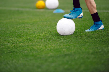 Football player with ball. Soccer player at the training pitch. Close up image of footballer standing with ball on grass fieldの写真素材