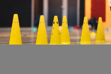 Row of Yellow Sports Training Cones on Shiny Surface of Wooden Sports Floor. Indoor Soccer, Basketball Training Fieldの写真素材