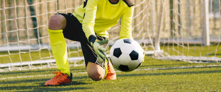 Young Football Galkeeper Catching Soccer Ball. Soccer Goalie in Action Saving Ball in a Goalの写真素材