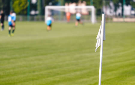 Football Corner White Flag. Soccer Turf Pitch in a Blurred Background. Players Kicking Soccer Gameの写真素材