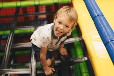 Happy Boy Having Fun In Play Area. Elementary Age Kid Playing on Play Center Construction. Amusement...