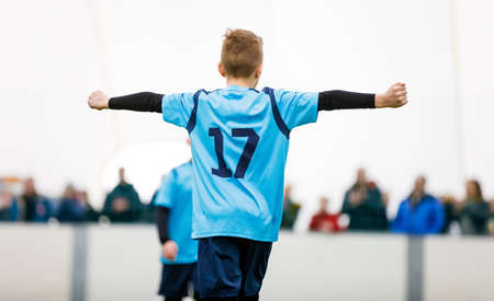 Happy soccer boy rising hands in success after scoring goal. School kids kicking football gameの写真素材