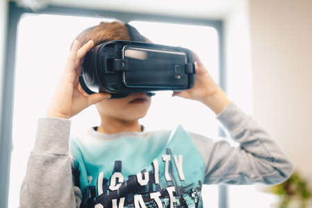 Children experiencing virtual reality at school. Amazed child with virtual reality headset sitting...