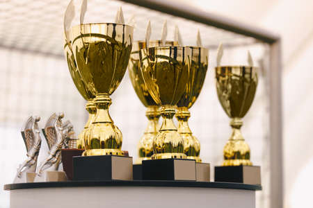 Photo of a set of golden trophies standing on the table. Golden cups for winners of sports competitionの写真素材