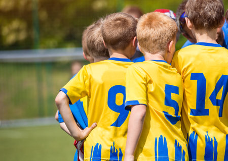Boys motivating each other in sports team before the football tournament match. Soccer kids with the coach. Portrait of a friendly football team gathered together with the coachの写真素材