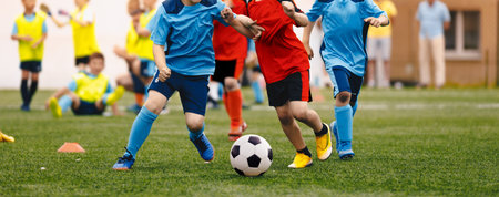 Young boys playing soccer game. Kids having fun in sports. Happy kids compete in football game.. Running soccer players. Competition between players running and kicking football ball. Football schoolの写真素材