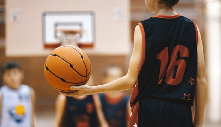 Kids Basketball Training. Young Basketball Player Dribble the Ball on the Wooden Court. Basketball Training Session For Kids. Sports Background of Youth Basketball Gameの写真素材