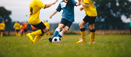 Football school. Happy kids compete in football game. Young boys playing soccer game. Kids having fun in sports. Running soccer players. Competition between players running and kicking football ballの写真素材