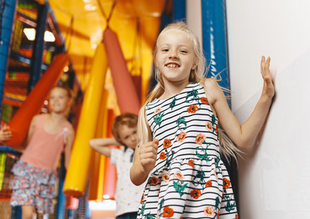 Kids jumping on playground cushions. Happy children jumping over obstacles in a Indoor playground. Kids playing on colorful playground at shopping mall. Children having fun togetherの写真素材