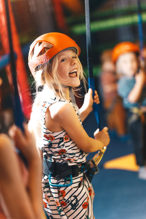 Kid in helmet having fun at bouldering wall. Joyful girl at indoor climbing wall. Child learning at climbing class. Family sport, healthy lifestyle, happy family.の写真素材