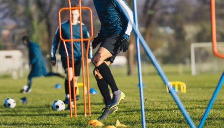 Football Player in Agility Training. Footballer Running Fast Between Training Hurdles. Soccer Practice Camp. Soccer Training Field in the Backgroundの写真素材