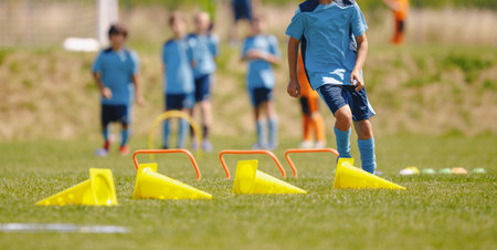 Football training camp for school kids. Children playing soccer training games outdoors. Kids running at obstacle courseの写真素材