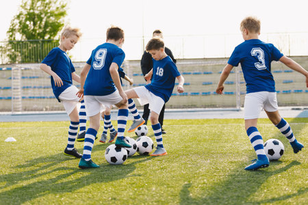 Young boys playing soccer training game. Junior football practice competition between players running in a duel and kicking a soccer ball. Training and football match between youth soccer teamsの写真素材