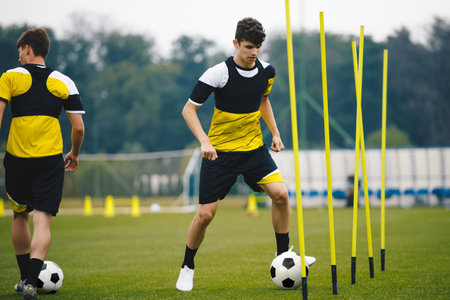 Junior Football Club Practice Session. Teenagers in Soccer Training Sportswea. Sports Educational Equipment. Youth Sports Player Running With Soccer Ball on Training Field.の写真素材