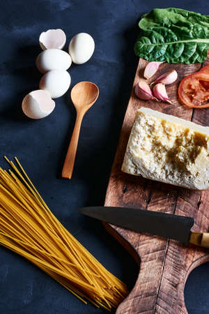 ingredients to prepare mediterranean pasta on a dark base with natural light