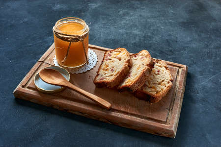jam accompanied with bread with fruits on a wooden board with a spoon on a blue background
